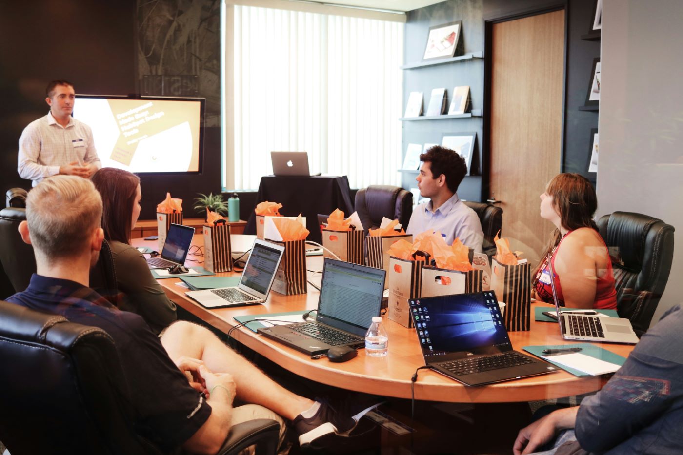 A workshop in a meeting room: one person presenting, the team following on laptops